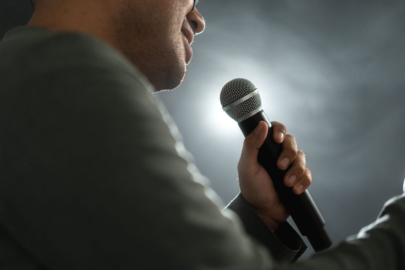 Person holding microphone, speaking on stage.